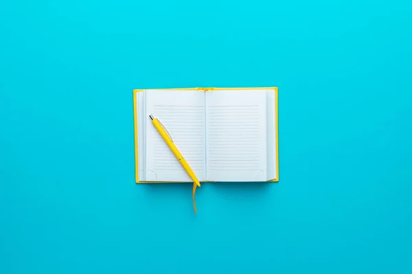 Bovenaanzicht van geopende notebook en pen op turquoise blauwe achtergrond met kopieerruimte — Stockfoto