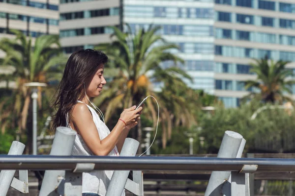 Retrato de menina lendo uma mensagem em seu smartphone sobre o fundo da cidade — Fotografia de Stock