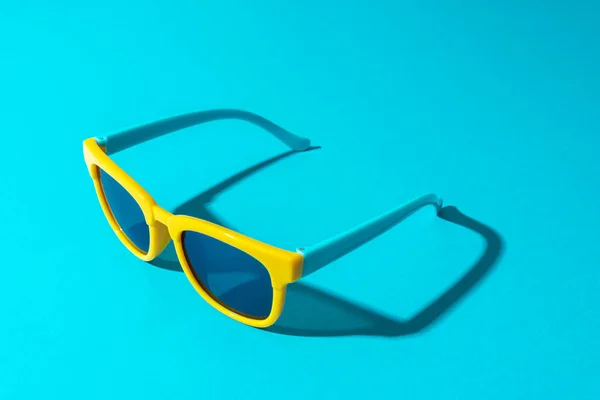 Plastikowe okulary przeciwsłoneczne na turkusowym tle w perspektywie z twardym cieniem — Zdjęcie stockowe