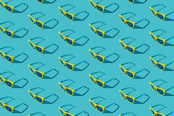 Plastic sunglasses pattern on turquoise blue background with hard shadow