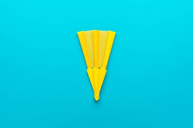 Turkuaz mavi arka planda sarı el vantilatörünün minimalist fotoğrafı.
