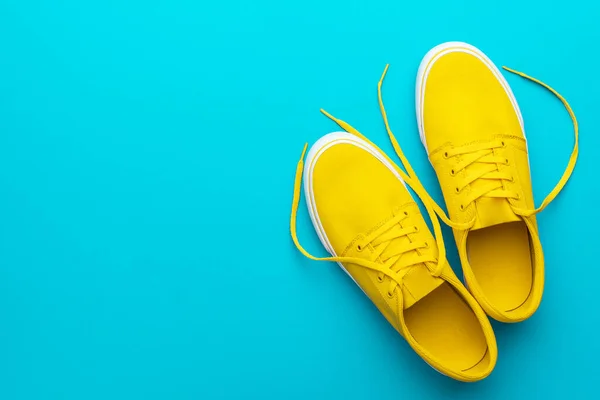 Top view of yellow untied sneakers on blue turquoise background with copy space — Stock Photo, Image