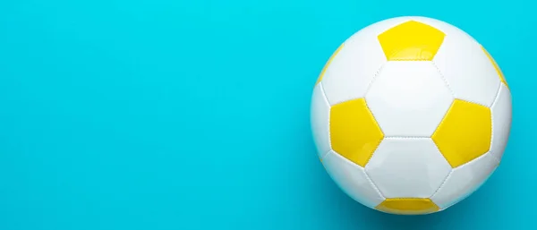 サッカーのコンセプトとして白と黄色のサッカーボールのトップビューの写真 コピースペースと右側の組成を持つ青ターコイズの背景に革サッカーボールのミニマリズムフラットレイ画像 — ストック写真
