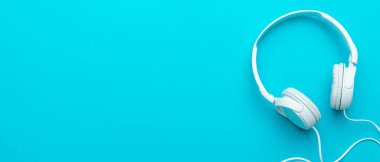 Kablolu beyaz kulaklıkların, mavi arka planda fotokopi alanı olan minimum fotoğrafı.