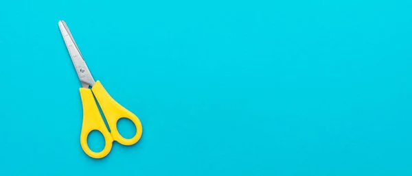 Плоская фотография желтых ножниц на синем фоне с пространством для копирования — стоковое фото