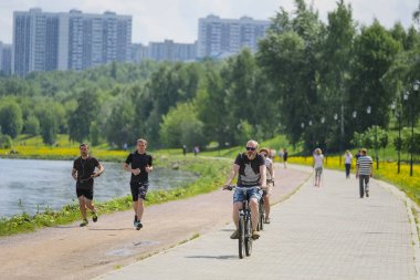 Moskova, Rusya - 13 Mayıs 2019: Moskova'daki Kolomenskoye parkının rayları üzerinde koşucular ve bisikletçilerin görüntüsü