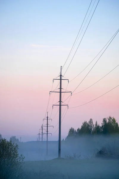 霧の中の日の出時の送電線支持構造 — ストック写真