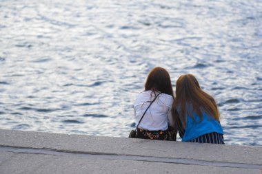 Saint-petersburg, Rusya - 14 Ağustos 2019: İki kız Saint-petersburg, Rusya'da Neva nehri kıyısında oturun