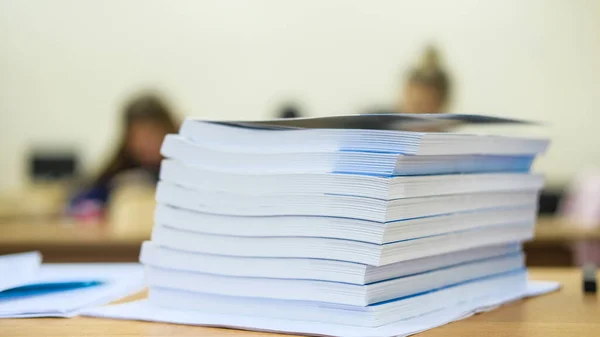 image of a stack of notebooks on the teacher\'s desk
