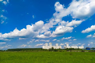 Bir yaz arazisi ve uzaklardan görülebilen bir şehri olan manzara.