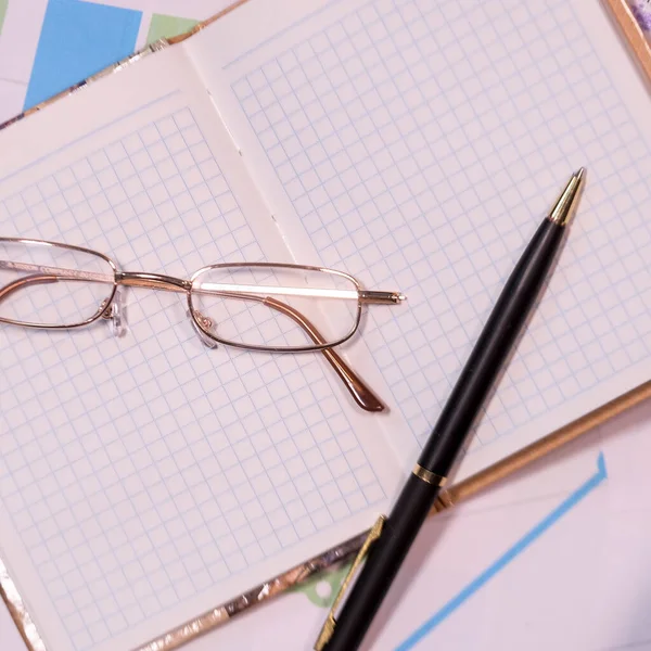 Afbeelding Van Glazen Pennen Liggend Een Open Notebook Een Bureaublad — Stockfoto