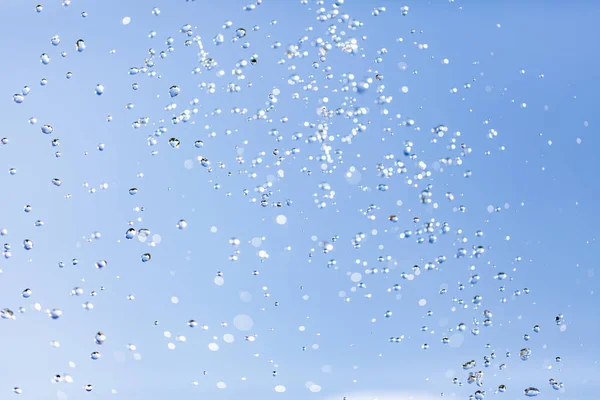 Vattendroppar i luften mot himlen — Stockfoto