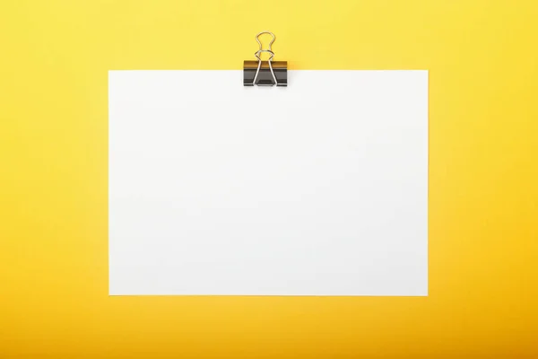 Papel en blanco con pinza sobre fondo amarillo. Concepto educativo con espacio de copia para sus ideas . — Foto de Stock