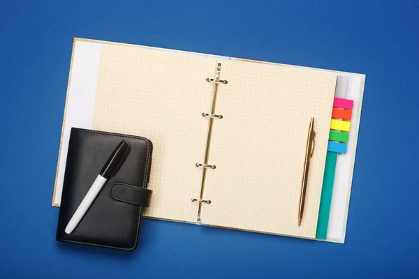 Cuaderno con rotulador y bolígrafo sobre fondo azul — Foto de Stock
