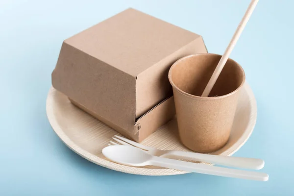 Açık mavi arka planda biyolojik olarak ayrıştırılabilir tek kullanımlık tabaklar. Geri dönüşüm kavramı