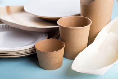 Açık mavi arka planda biyolojik olarak ayrıştırılabilir tek kullanımlık tabaklar. Geri dönüşüm kavramı