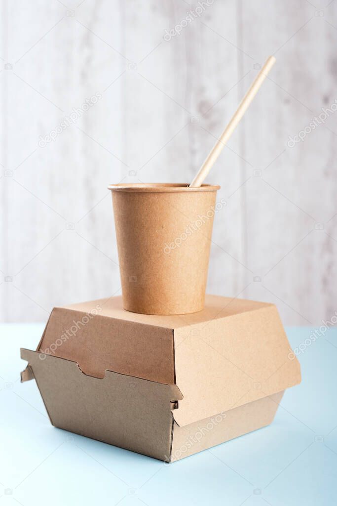 A cup with drinking straw standing on burger box