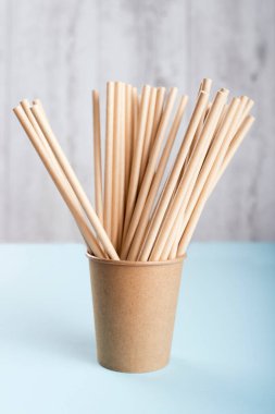 Açık gri arka planda pipet içen biyolojik çözünebilir fincan. 