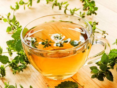 Beyaz ahşap arka planda bir fincan Melissa çayı..