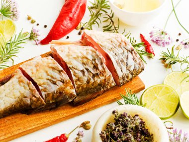 Beyaz ahşap arka planda baharatları olan çiğ tatlı su altın haçbalığı. Sığ dof.