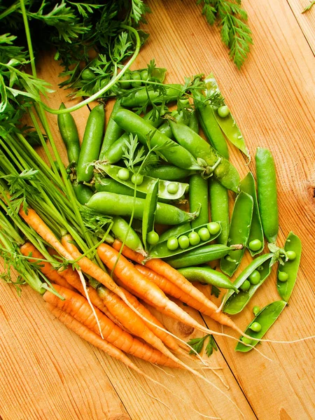 Frische Baby Karotten Und Grüne Erbsen Auf Dem Hölzernen Hintergrund — Stockfoto