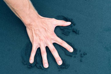 Sağ erkek el kumsaldaki kumu itiyor.