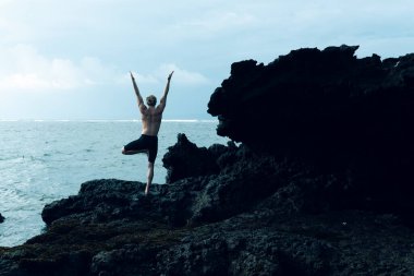 Atletizm sporcusu dışarıda yoga yapıyor.