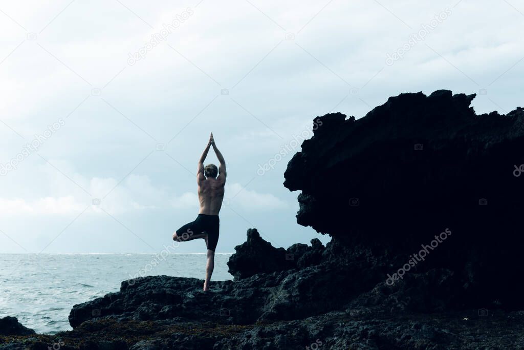 Athlete man practicing yoga outdoors photograph