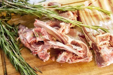 kesme tahtası taze kuzu kaburga ile rosemary ile dekore edilmiştir.