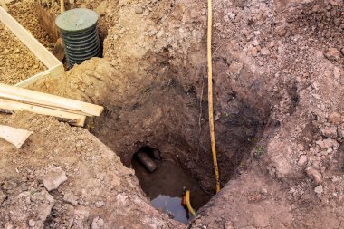 view of the construction site with trenches for the Foundation and pump pumping water for dehumidification clipart