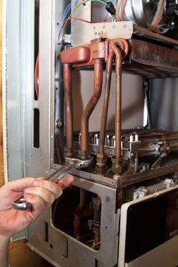 worker installs the heat exchanger after descaling on a workplace in the gas boiler clipart