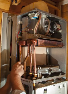 worker installs the heat exchanger after descaling on a workplace in the gas boiler clipart