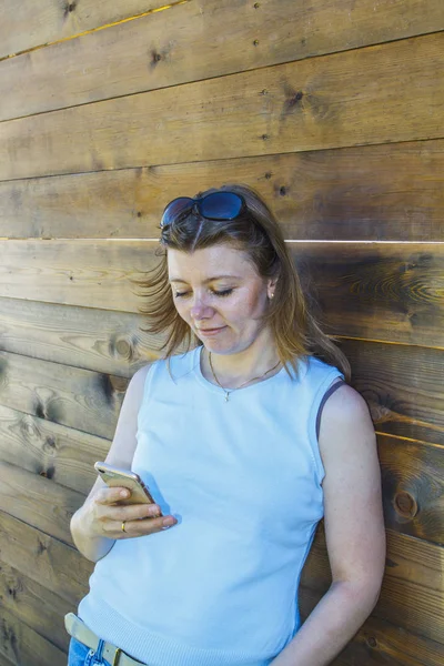 Beautiful Girl Blue Shirt Using Smart Phone Wooden Wall Outdoors — Stock Photo, Image