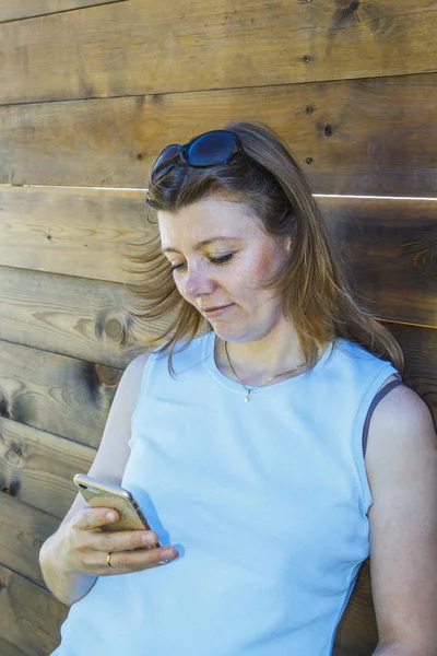 Beautiful Girl Blue Shirt Using Smart Phone Wooden Wall Outdoors — Stock Photo, Image