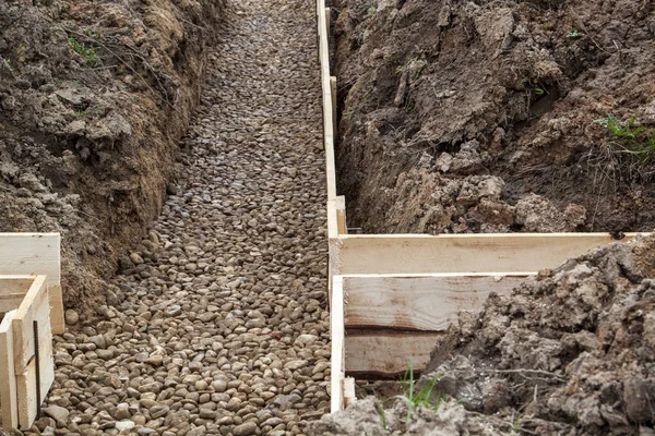 未処理の型枠ボードと基礎の下を掘った溝の下部に瓦礫のクローズ アップ表示 — ストック写真