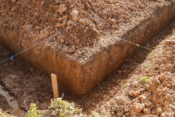 Angle of the trench dug by hand under the Foundation or for laying drainage and lines drawn from a rope for evenness — Stock Image Angle Trench Dug Hand Foundation Laying Drainage Lines Drawn Rope Royalty Free Stock Images