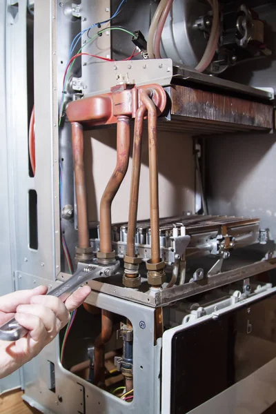 Worker unscrews the nuts to remove the heat exchanger from the gas boiler, for further descaling — Stock Image Worker Unscrews Nuts Remove Heat Exchanger Gas Boiler Further Descaling Royalty Free Stock Photos