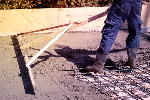 Arbeiter nivellieren frische Betonplatten mit einem speziellen Arbeitsgerät — Stockfoto