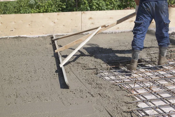 Worker leveling fresh concrete slab with a special working tool — Stock Photo, Image