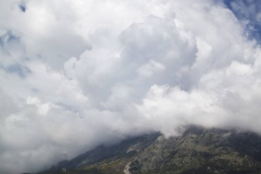 Mavi gökyüzü arka planı üzerinde beyaz bulutları olan dağlar