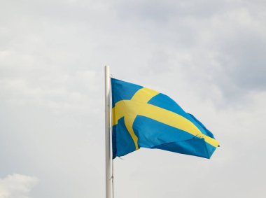 Bulutlar arka plan ile mavi bir gökyüzünde İsveç Bayrağı