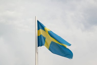 Bulutlar arka plan ile mavi bir gökyüzünde İsveç Bayrağı