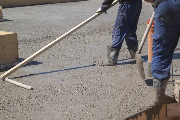 Працівник вирівнює свіжу бетонну плиту спеціальним робочим інструментом — стокове фото