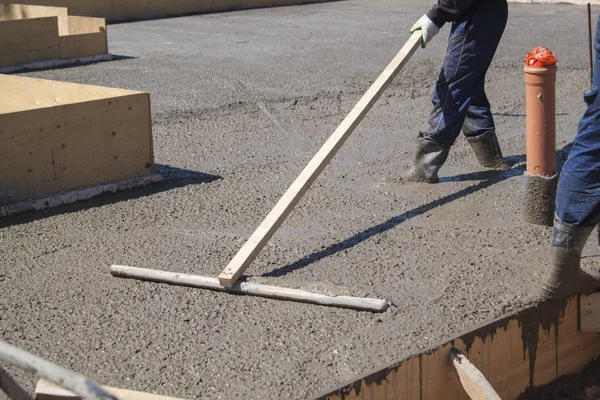 특수 작업 도구로 신선한 콘크리트 슬래브를 평준화하는 작업자 — 스톡 사진