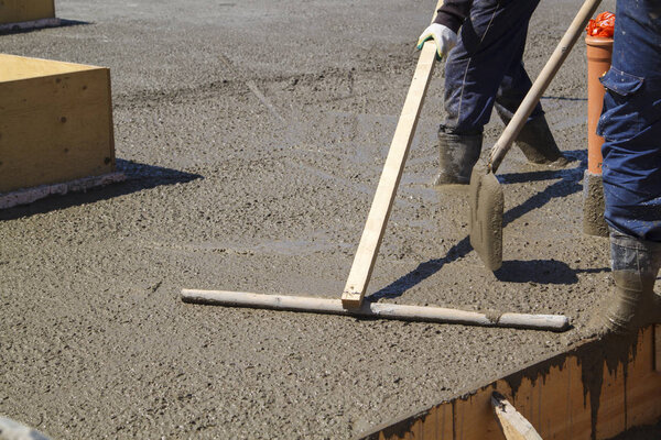two workers in rubber boots stands in uncluttered cement and lev