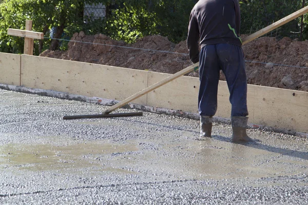 Працівник вирівнює свіжу бетонну плиту спеціальним робочим інструментом — стокове фото