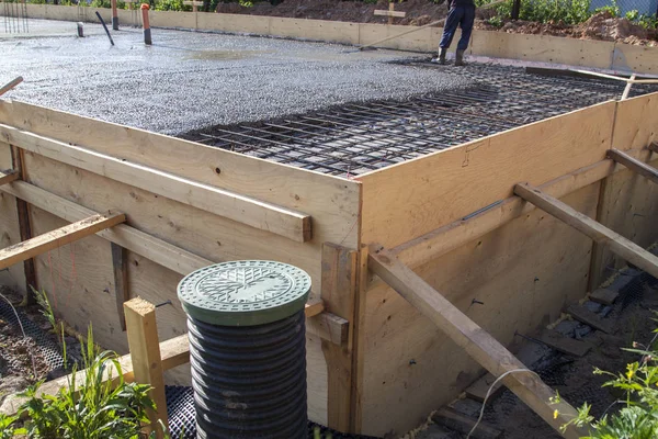 Рабочий выравнивает свежую бетонную плиту специальным рабочим инструментом — стоковое фото