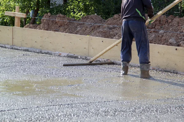 worker in rubber boots stands in uncluttered cement and leveling