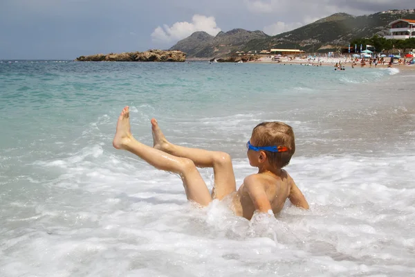 Kleiner Junge spielt mit splahes Wellen des Meeres — Stockfoto