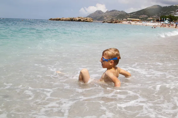 Kleiner Junge spielt mit splahes Wellen des Meeres — Stockfoto
